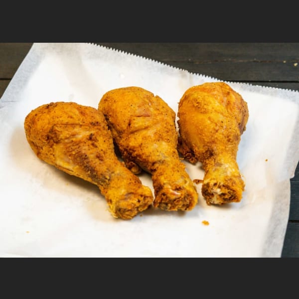 Three crispy fried chicken drumsticks from M&M Chicken & Fish on white parchment paper.